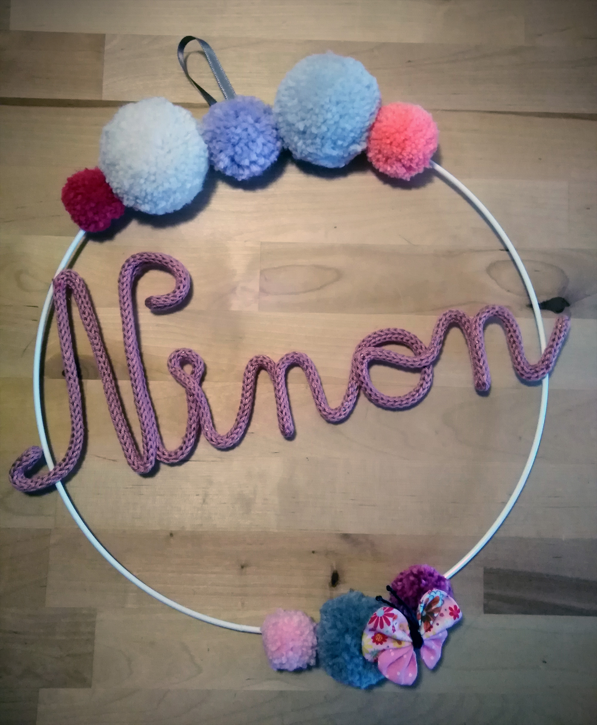 Ninon en tricotin sur une couronne de pompons